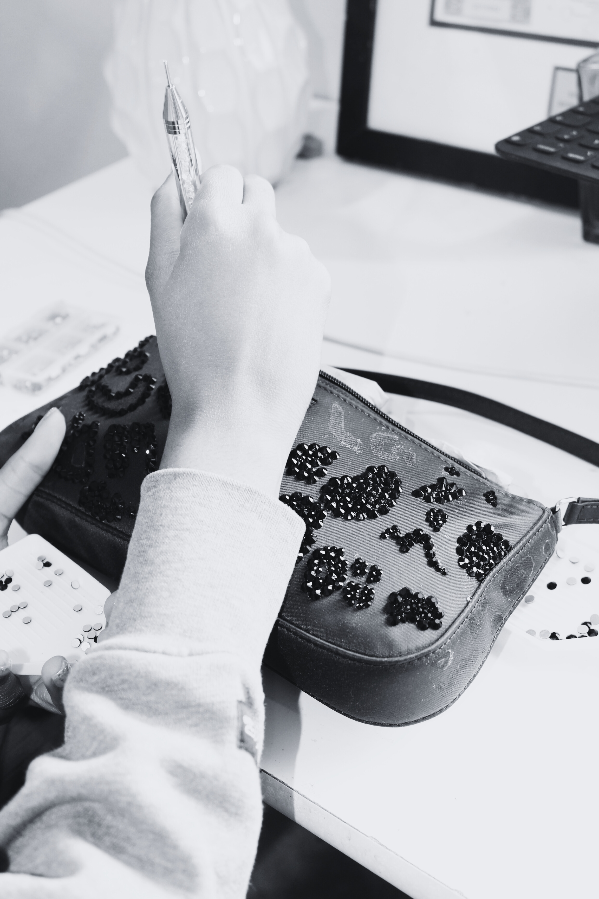 Rhinestone being applied to bag. Black and white photo.